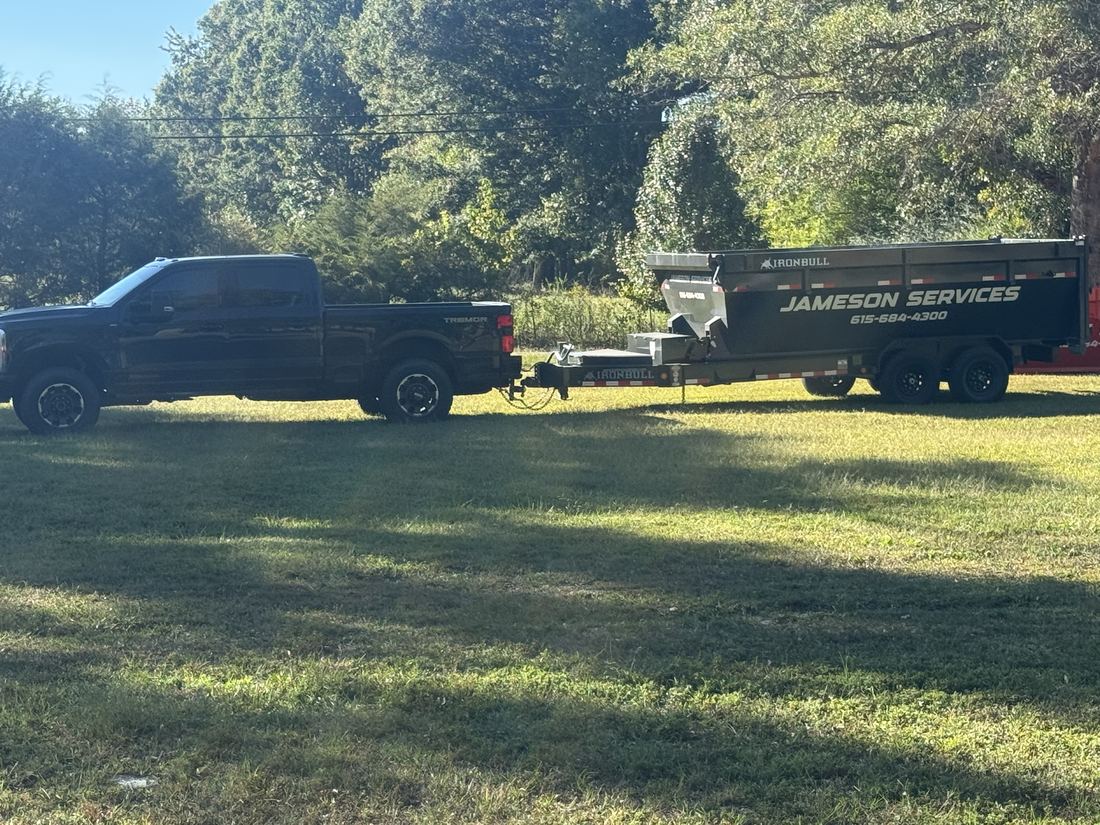 Truck towing a Jameson Services dumpster trailer for delivery