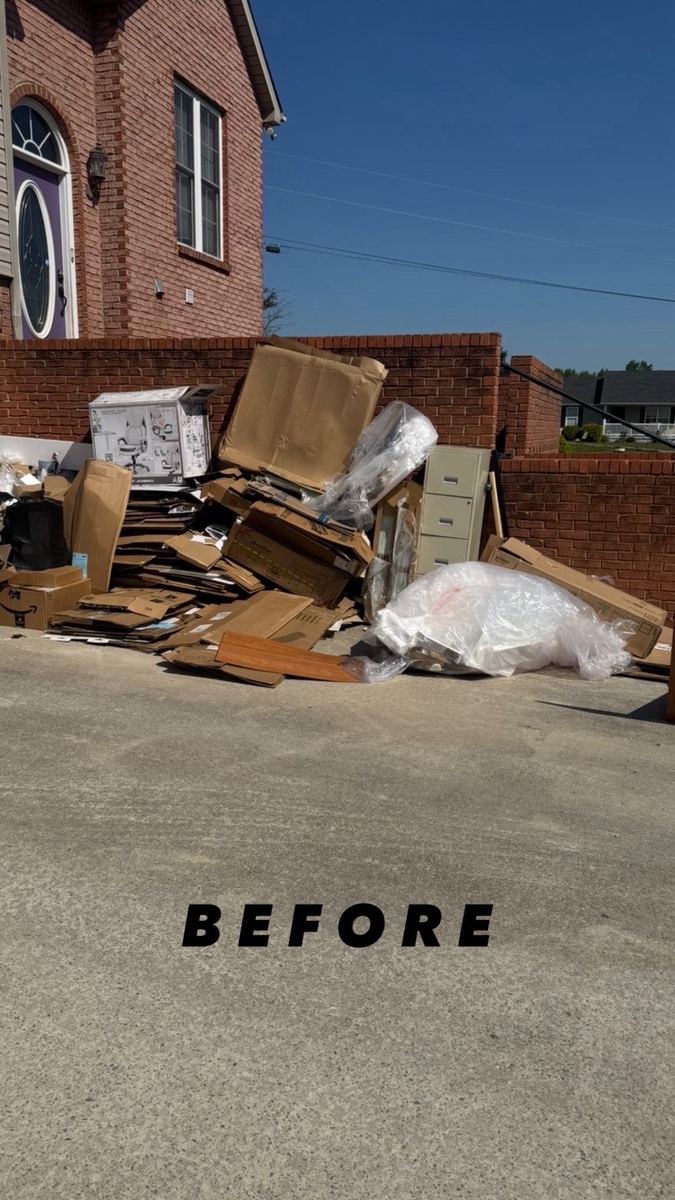 Pile of boxes and old furniture on a driveway before junk removal